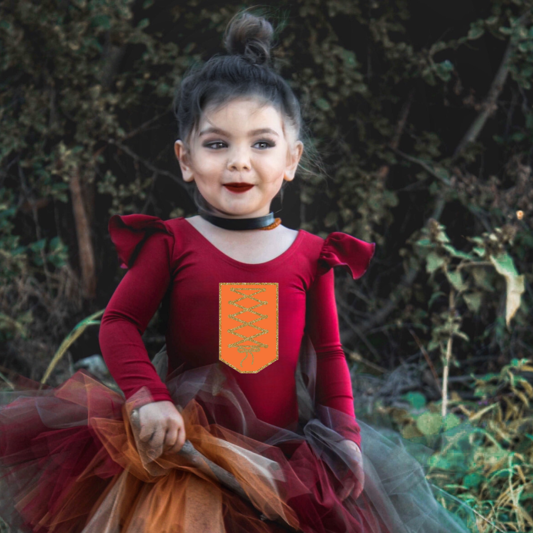 Little girl wearing burgundy ruffle long sleeve leotard with "Mary" inspired design on front.